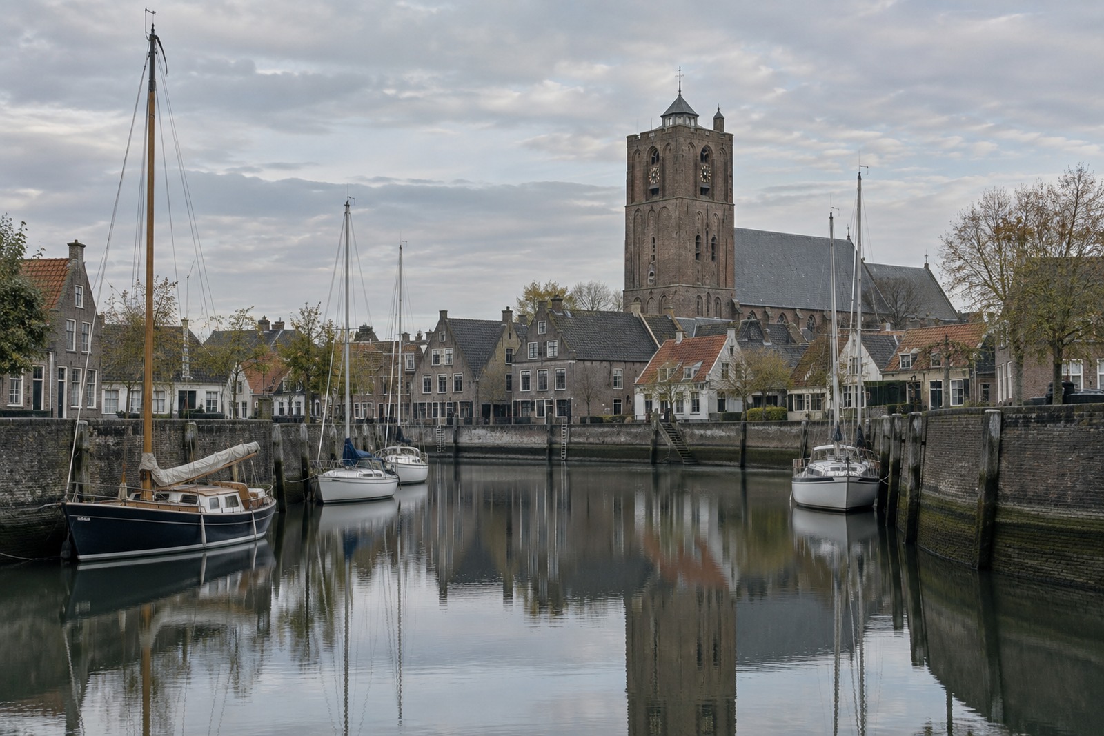 Bakstenen kerktoren boven de daken van een verzande oude havenstad