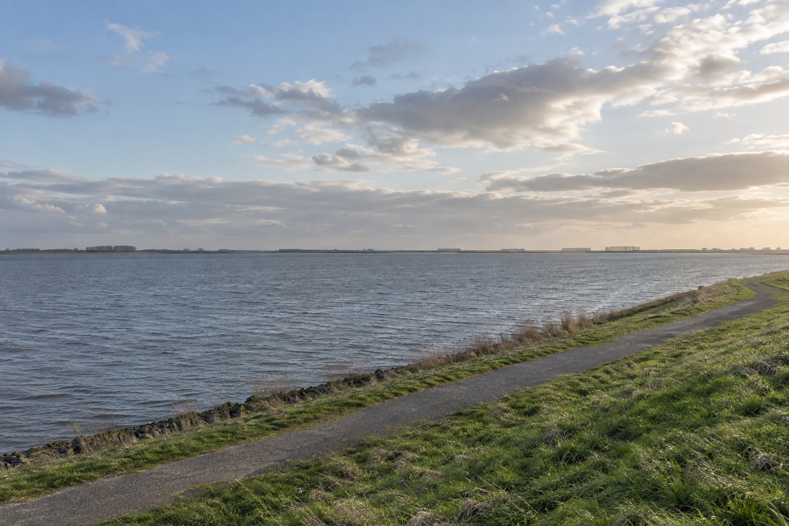 Uitzicht over de brede waterloop van het Haringvliet, gezien vanaf de kruin van een dijk