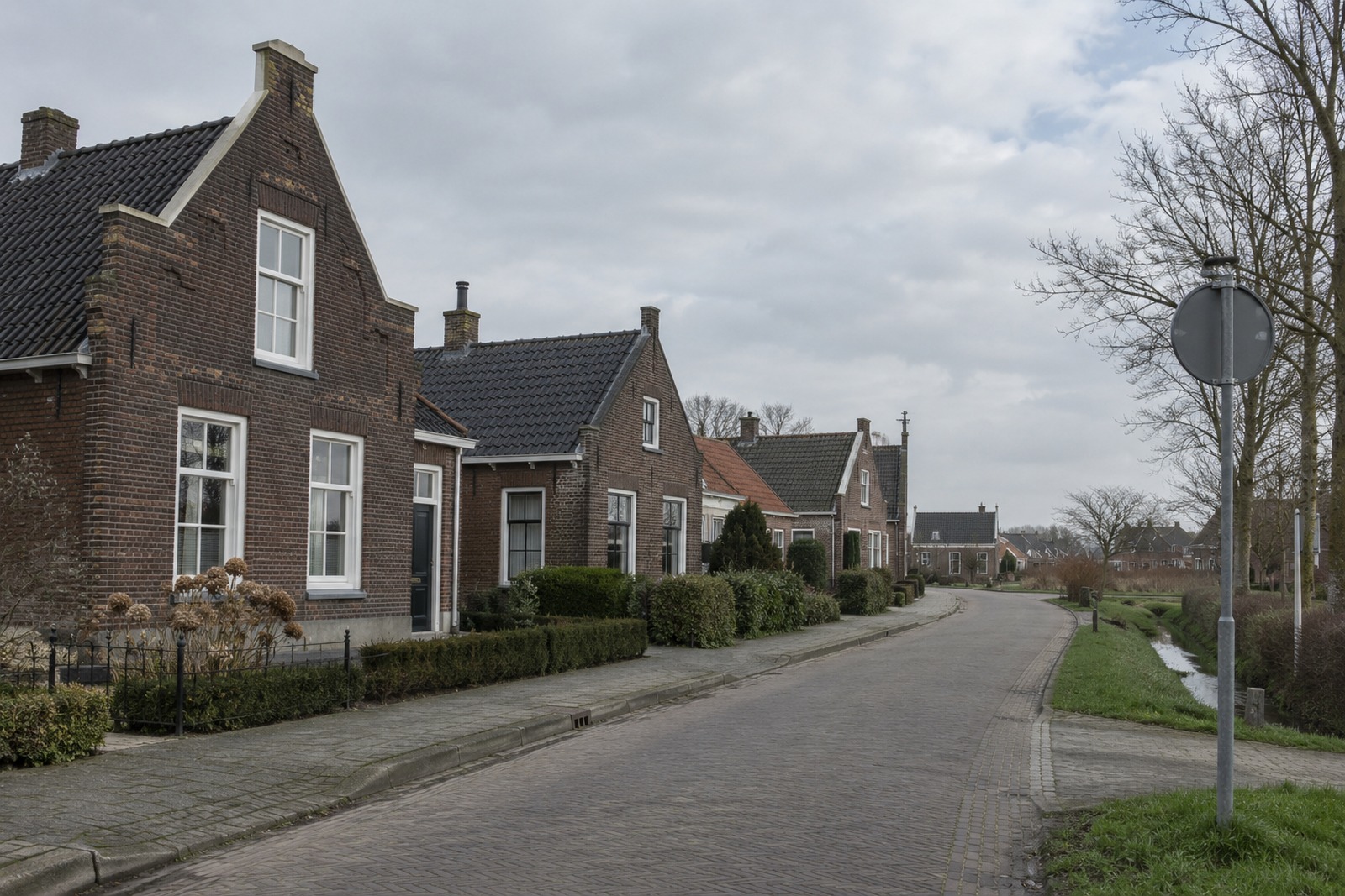 dorpsbord langs een polderweg op het eiland onder een lage lucht
